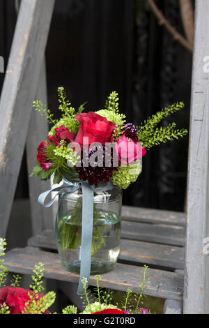 Bouquet of hydrangea, carnations and hydrangeas in a glass jar on the stairs Stock Photo