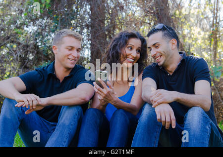 Three young adults laughing outside with smart phone Stock Photo