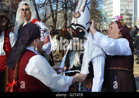 Local women with traditional folk costumes and kukeri masks on Surva festival in Pernik, Bulgaria Stock Photo
