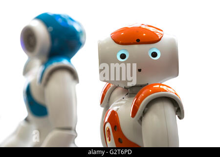 Small robots with human face and body - humanoid. Artificial Intelligence - AI. Orange and blue robots isolated on white backgro Stock Photo