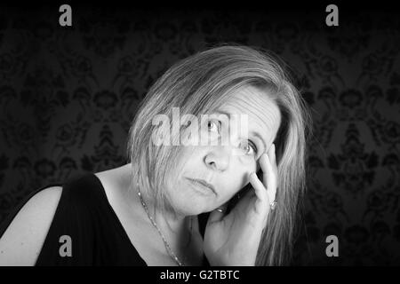 Black and white of woman looking sad on black damask Stock Photo