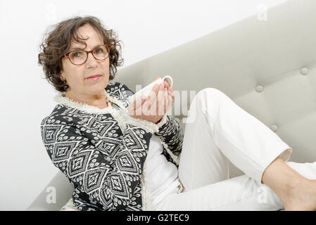 beautiful mature woman drinking tea on the sofa Stock Photo
