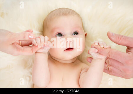 Parents holding baby infant hands. Top view. Stock Photo