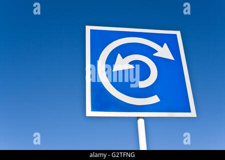 Roundabout sign over blue sky Stock Photo