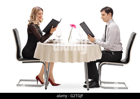 Young couple reading the menu and sitting at a restaurant on a date isolated on white background Stock Photo
