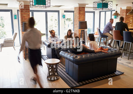 Busy Reception Area Of Modern Boutique Hotel With Guests Stock Photo