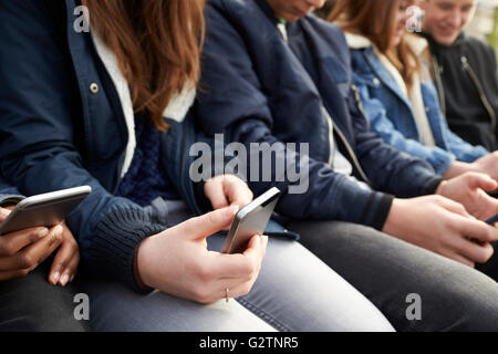 Close Up Of Teenage Friends Using Mobile Phones