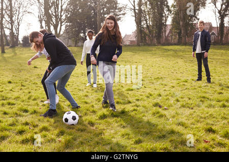 Group Of Teenagers Playing Soccer In Park Together Stock Photo