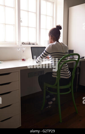 Teenage Girl Sitting At Desk In Bedroom Using Laptop Stock Photo