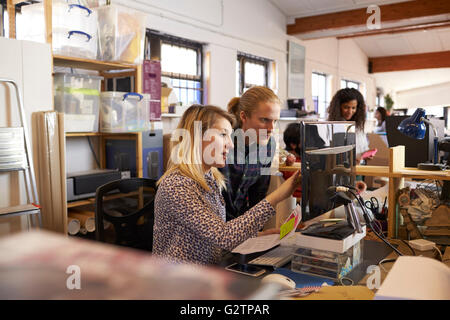Two Designers Working Together At Computer In Busy Office Stock Photo