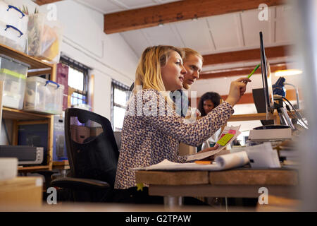 Two Designers Working Together At Computer In Busy Office Stock Photo