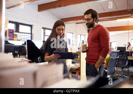 Two Designers Using Digital Tablet In Busy Office Stock Photo