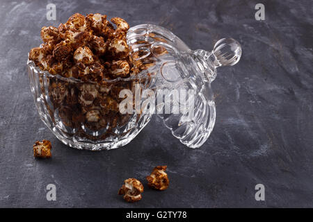 Closeup of sweet chocolate popcorn in a crystal bowl on wooden background Stock Photo