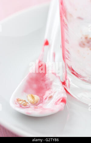 A dirty and used glass and spoon on a plate after dinner. Stock Photo