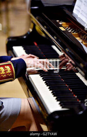 Hands of a woman part of a military orchestra performing at a piano during a concert Stock Photo