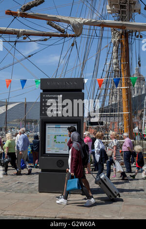 Signs to different destinations for Crowds, tourists, day-trippers, visitors and tourists, visit the tall ships event in dockland at the International Mersey River Festival 2016, UK. Directions to Albert dock, Kings dock.  Princess dock, Waterfront, The Tate Liverpool, Information Toilets, and The beatles story, Merseyside. Stock Photo