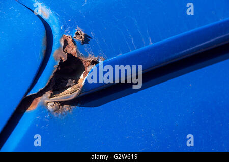 Extreme closeup of severe rust corrosion on roof corner of blue motor vehicle Stock Photo