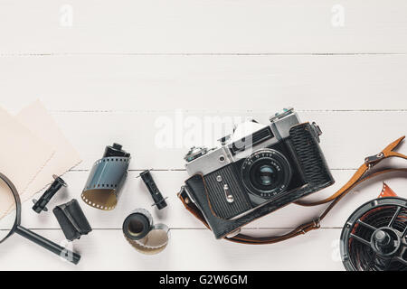 Retro camera, old photo film rolls, empty photos and magnifier on wooden background. Flat lay, top view. Stock Photo