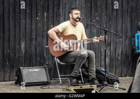 LONDON, UK - AUGUST 20, 2015: Street musician plays acoustic guitar near at Camden Town Market. Stock Photo