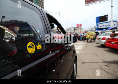 Driver using in car wifi in tourist vehicle while parked in street outside market, Miraflores, Lima, Peru Stock Photo