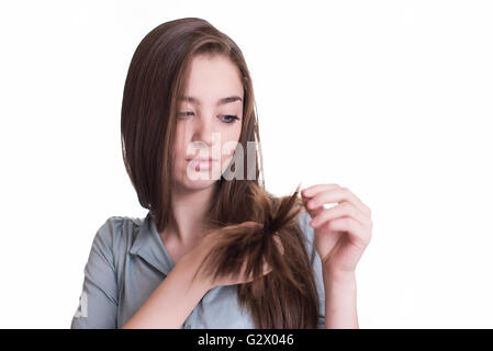 Young woman looking at split ends. Damaged long hair Stock Photo