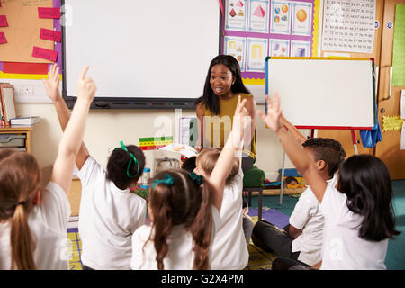 Teacher Asks Elementary School Pupils Question In Classroom Stock Photo