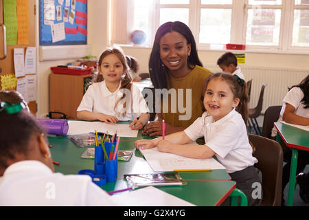 Female Elementary School Teacher Helping Pupils At Desk Stock Photo - Alamy
