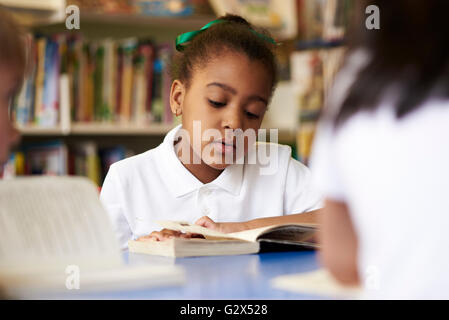Female Elementary School Pupil Reading In Library Stock Photo