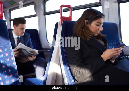 Businesswoman Reading Text Message On Train During Commute Stock Photo
