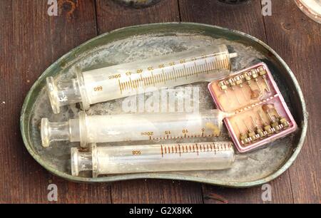 Old medical syringes and hypodermic needles in corroded tray Stock Photo
