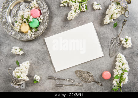 Macaroon cakes and note paper for text or recipe. Vintage style background with white lilac flowers Stock Photo