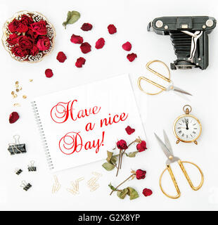 Flat lay with sketchbook, red rose, vintage camera, scissors on white background. Red flowers. Have a nice Day! Stock Photo