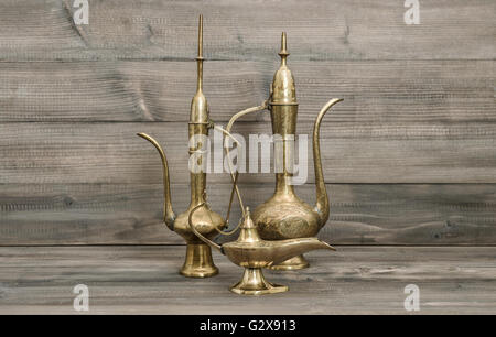 Vintage arabic jug, vase, lamp, teapot. Golden oriental decorations on wooden background Stock Photo