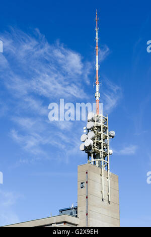 Telecommunication antenna with microwave link antennas over a blue sky Stock Photo