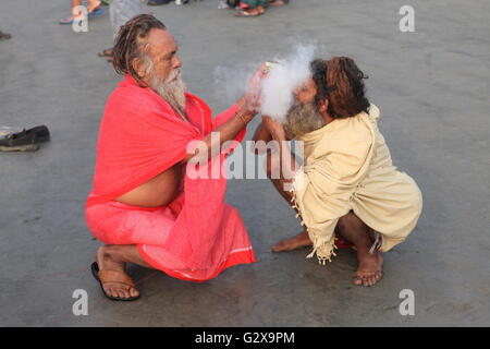 one monk helping the other to light up a local made beedi on a chilly winter morning during ganga sagar festival in west bengal Stock Photo