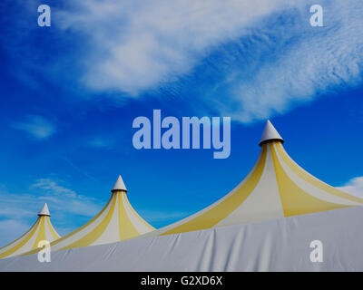 Upper part of a big colorful plastic tent. Blue sky and white clouds in background Stock Photo