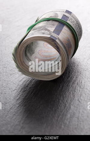 money roll dollars on a slate table. Stock Photo