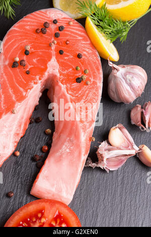 red fish steak with spices and vegetables on a slate table. Stock Photo