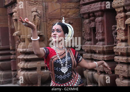 striking pose of an odissi dancer against the backdrop of a temple with sculptures in bhubaneswar Stock Photo