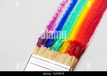 Flat paintbrush and multicolor rainbow brush strokes on white artist canvas Stock Photo