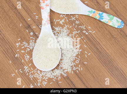 Raw white rice in spoon on wooden background Stock Photo