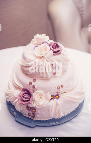 three-tiered beautiful wedding cake with roses on the table Stock Photo