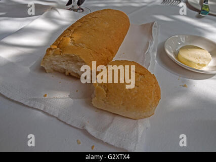 Crusty white bread with a dish of butter on a white tablecloth Stock Photo