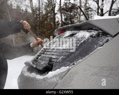 Scraping ice from the back windsheld of a car in winter Stock Photo