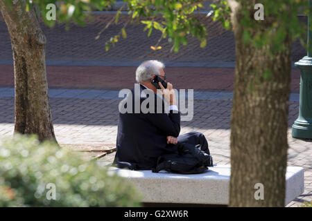 Businessman in a suit with white hair talks on a mobile phone Stock Photo