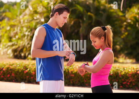 Young people doing sport activities, girl and friend running, using fit watch, man and woman jogging on the street. Concept of e Stock Photo