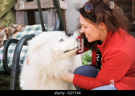 Happy young woman with white fluffy Samoyed dog Stock Photo