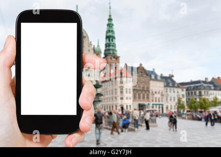 travel concept - tourist photographs Amagertorv the central square in Copenhagen, Denmark on smartphone with cut out screen with Stock Photo