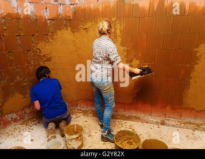 applying natural clay plasters on a wall, natural way without technology. Stock Photo