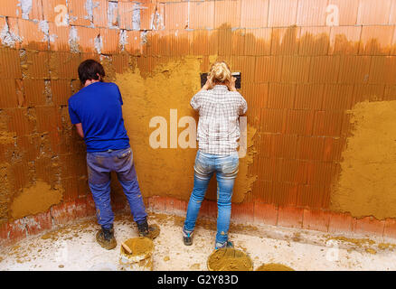 applying natural clay plasters on a wall, natural way without technology. Stock Photo